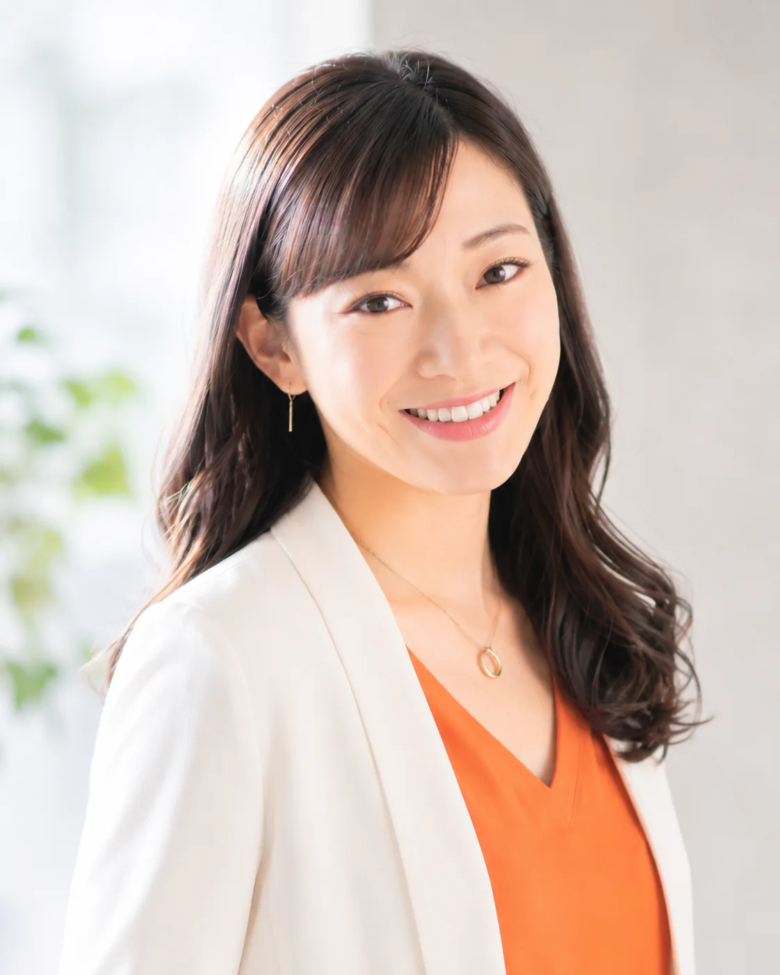 白いジャケットとオレンジの服を着た、笑顔の女性